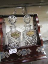 A mid-20th century tantalus containing two glass decanters with spirit labels
