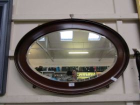 An oval mahogany framed bevel glass wall mirror