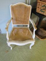 An early 20th century continental style pale blue painted open armchair with distressed cane seat