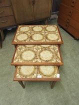 A nest of three mid-20th century tile topped teak occasional tables