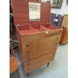 A mid-20th century teak chest of five drawers with lift up lid concealing storage and mirror