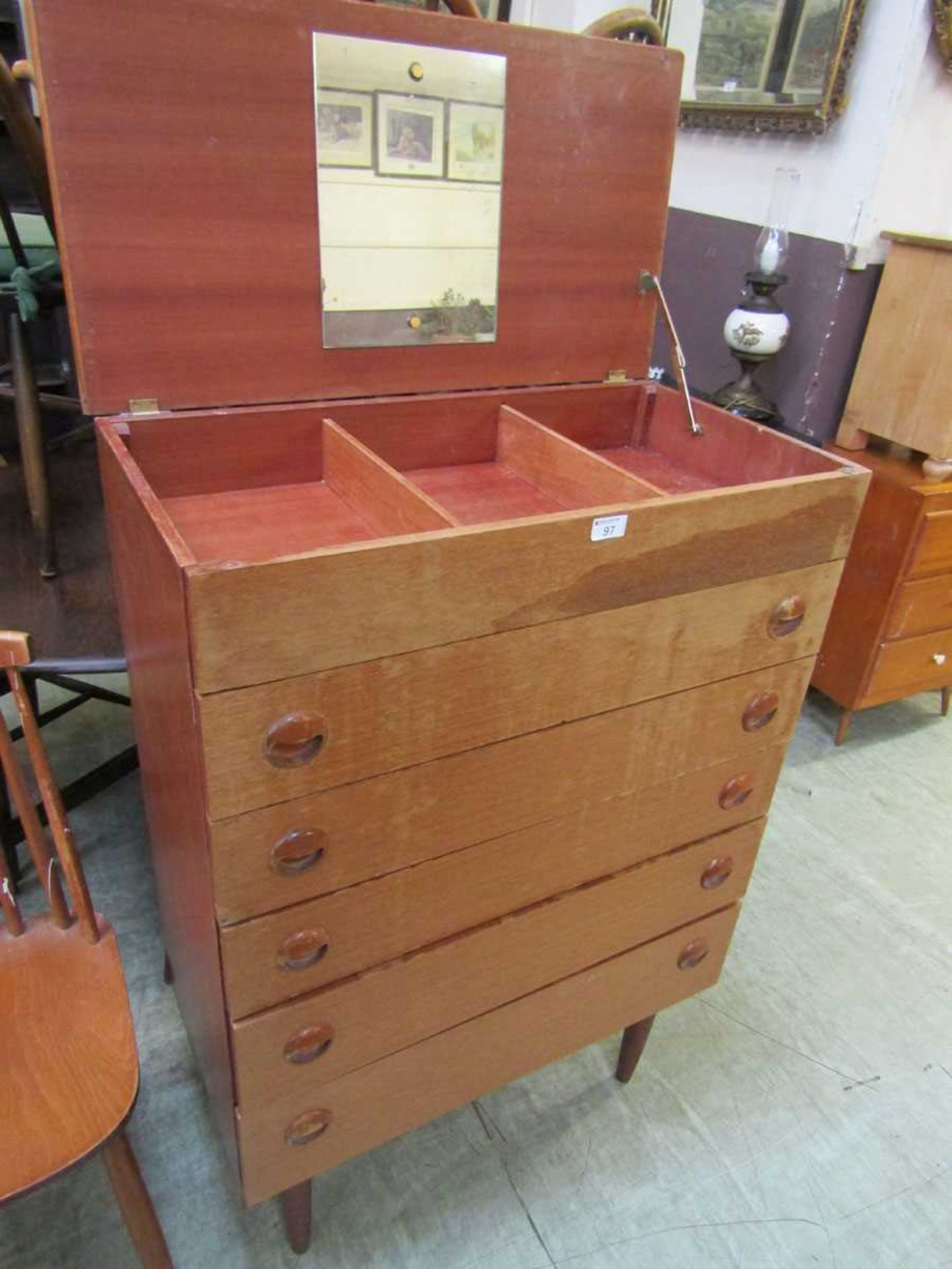 A mid-20th century teak chest of five drawers with lift up lid concealing storage and mirror