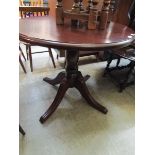 A stained pine pedestal circular dining table