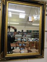 A reproduction black and gilt framed rectangular bevel glass wall mirror