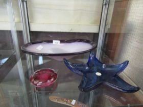 A blue glass Spanish starfish shaped bowl together with a purple glass bowl and a red glass
