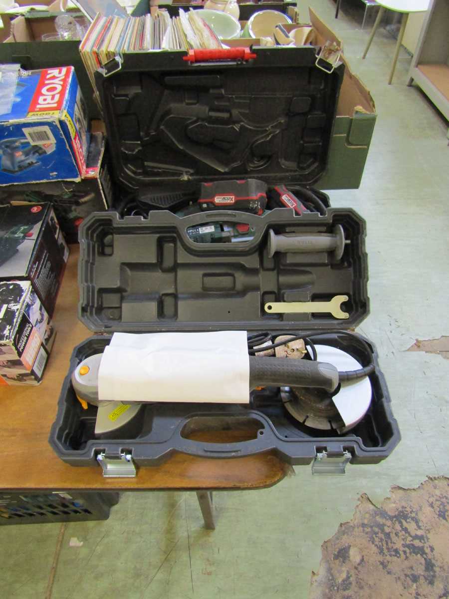 A boxed Parkside battery saw with two batteries together with a boxed Titan angle grinder