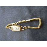 A 9ct gold ladies' wristwatch with a yellow metal sprung strap