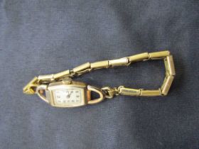 A 9ct gold ladies' wristwatch with a yellow metal sprung strap