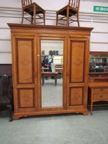 An Edwardian oak and burr walnut compactum having a central mirrored door flanked by cupboard doors,