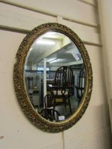 An ornate gilt framed oval bevel glass wall mirror