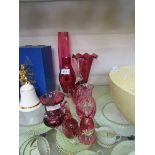 An assortment of eight pieces of cranberry glassware to include bud vases, bell, paperweight in