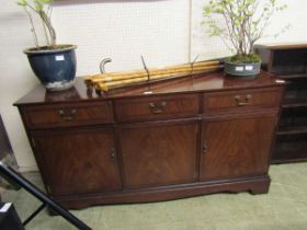 A reproduction mahogany sideboard having three drawers above cupboard doors