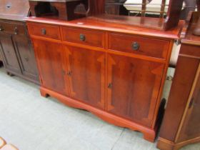 A modern yew sideboard having three drawers above cupboard doors