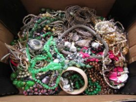 A carton containing a selection of costume jewellery to include beads, necklaces, bangles, brooches,