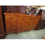 A reproduction break front yew sideboard having a centre drawer above cupboard doors flanked by