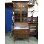 An early 20th century mahogany inlaid bureau bookcase having a two door glazed top section, the base