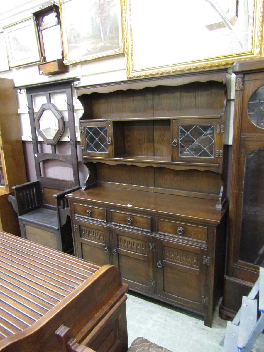 A mid-20th century oak dresser having a raised top section with open storage being flanked by leaded