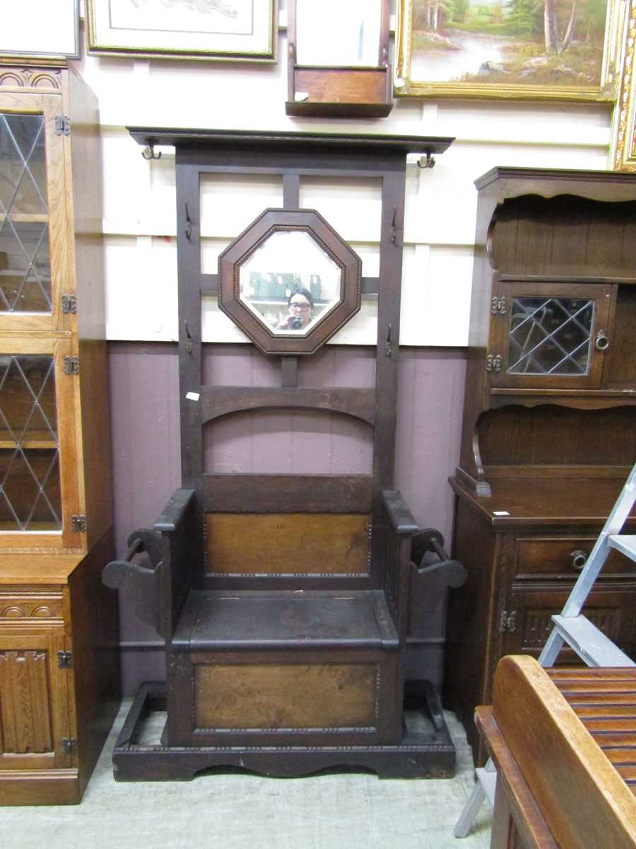 An early 20th century oak hall stand having a hexagonal framed mirror with a seated lift up lid