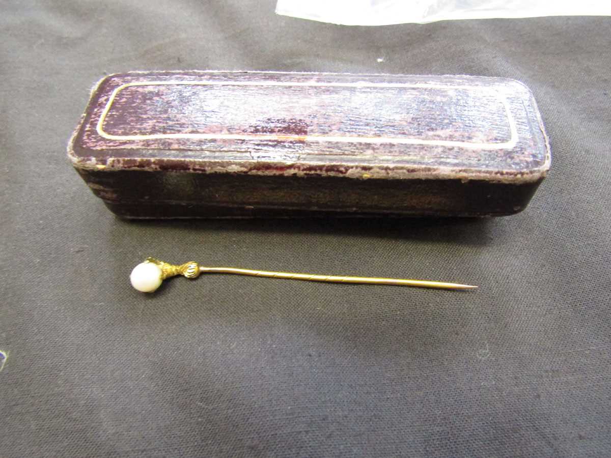 A yellow metal tie pin having a small pearl held in with claw