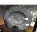 A pewter barbers bleeding bowl depicting classical figures with embossed text 'Le Milanogene