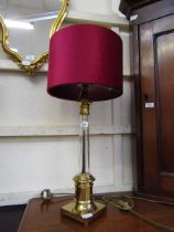 A modern brass and glass effect table lamp with deep red shade