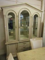 A modern continental limed oak effect cabinet having a three door arch topped glazed section, the