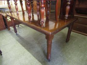 An Edwardian walnut wind out dining table with one centre leaf