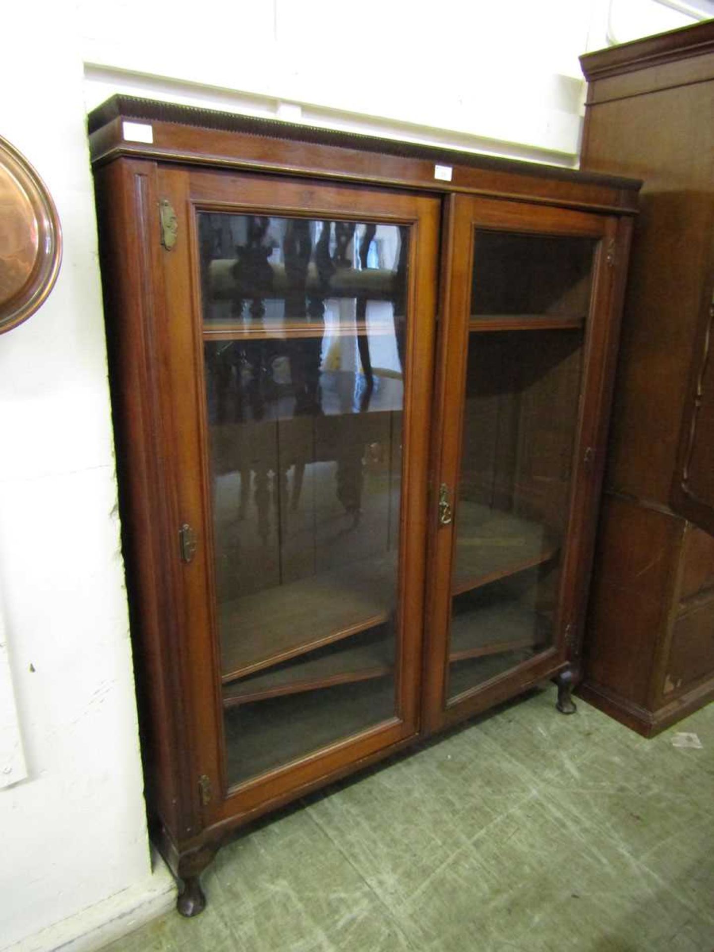 An early 20th century walnut glazed two door bookcase on cabriole supports