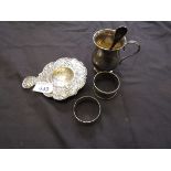 A silver embossed strainer together with two napkin rings, a small tankard, and a silver