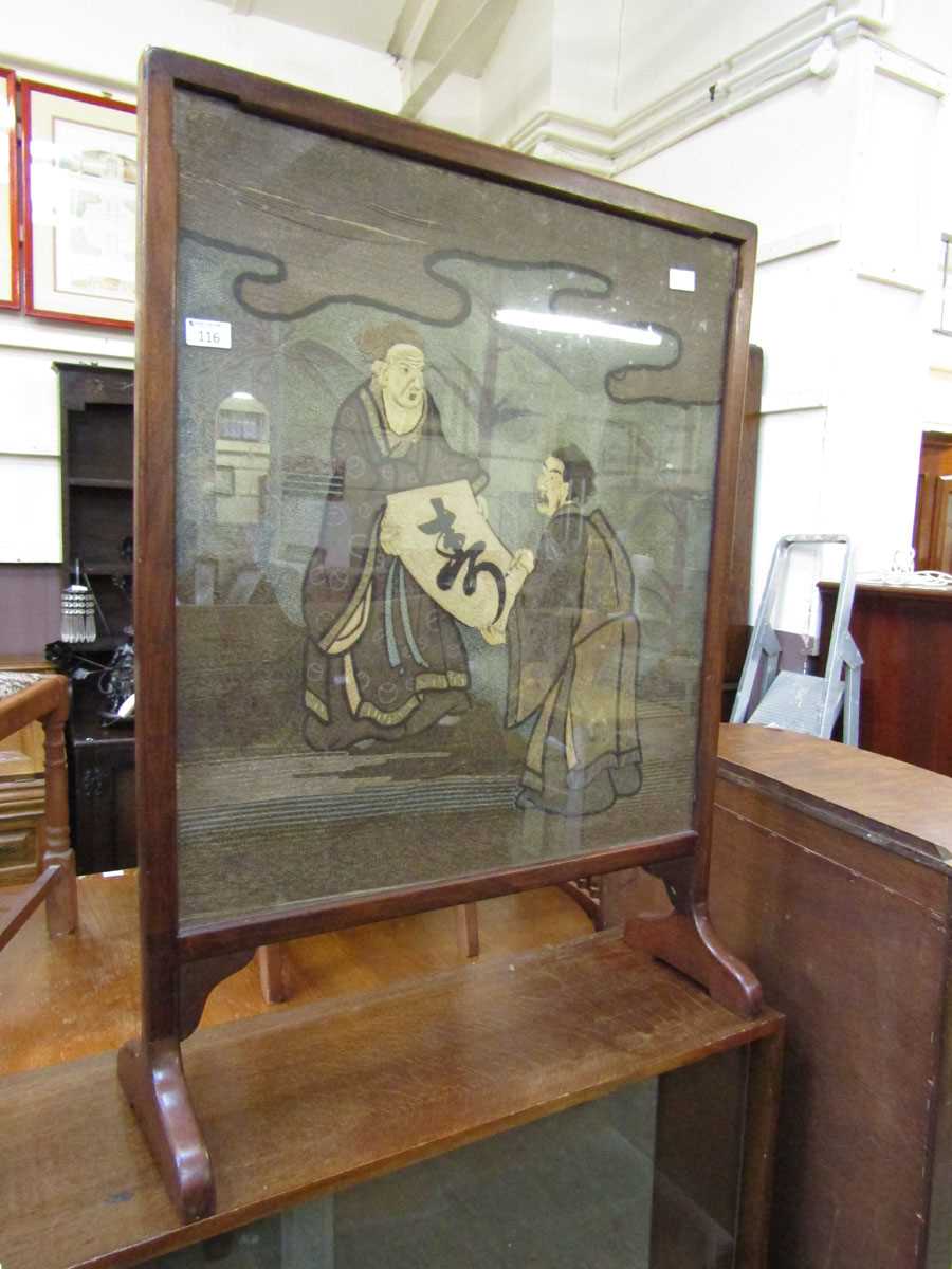 An early 20th century mahogany framed firescreen having a woolwork eastern scene under glass