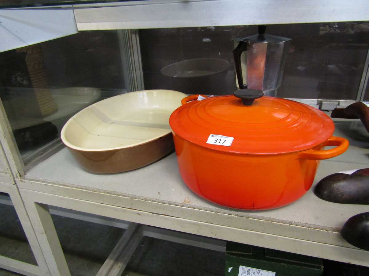 An orange lidded Le Creuset twin handled cooking pot along with a stainless steel cafetierre and a
