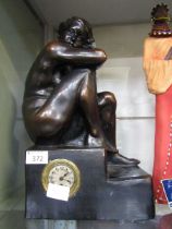 A black painted moulded mid-20th century timepiece in the form of a step with young lady sat atop No