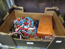 A carton containing an assortment of costume jewellery to include beads, bangles, necklaces, etc