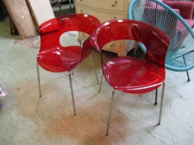 A pair of red Perspex and chrome legged chairs