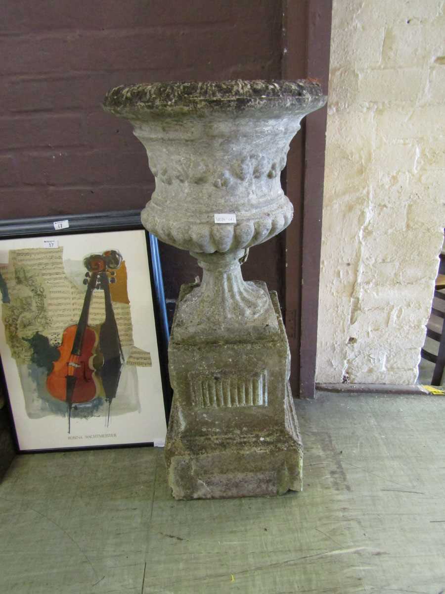 A weathered stoneware urn on plinth