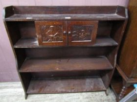 An early 20th century low level bookcase having two carved doors