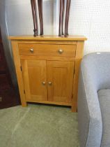 A modern oak cabinet having single drawer above a pair of cupboard doors