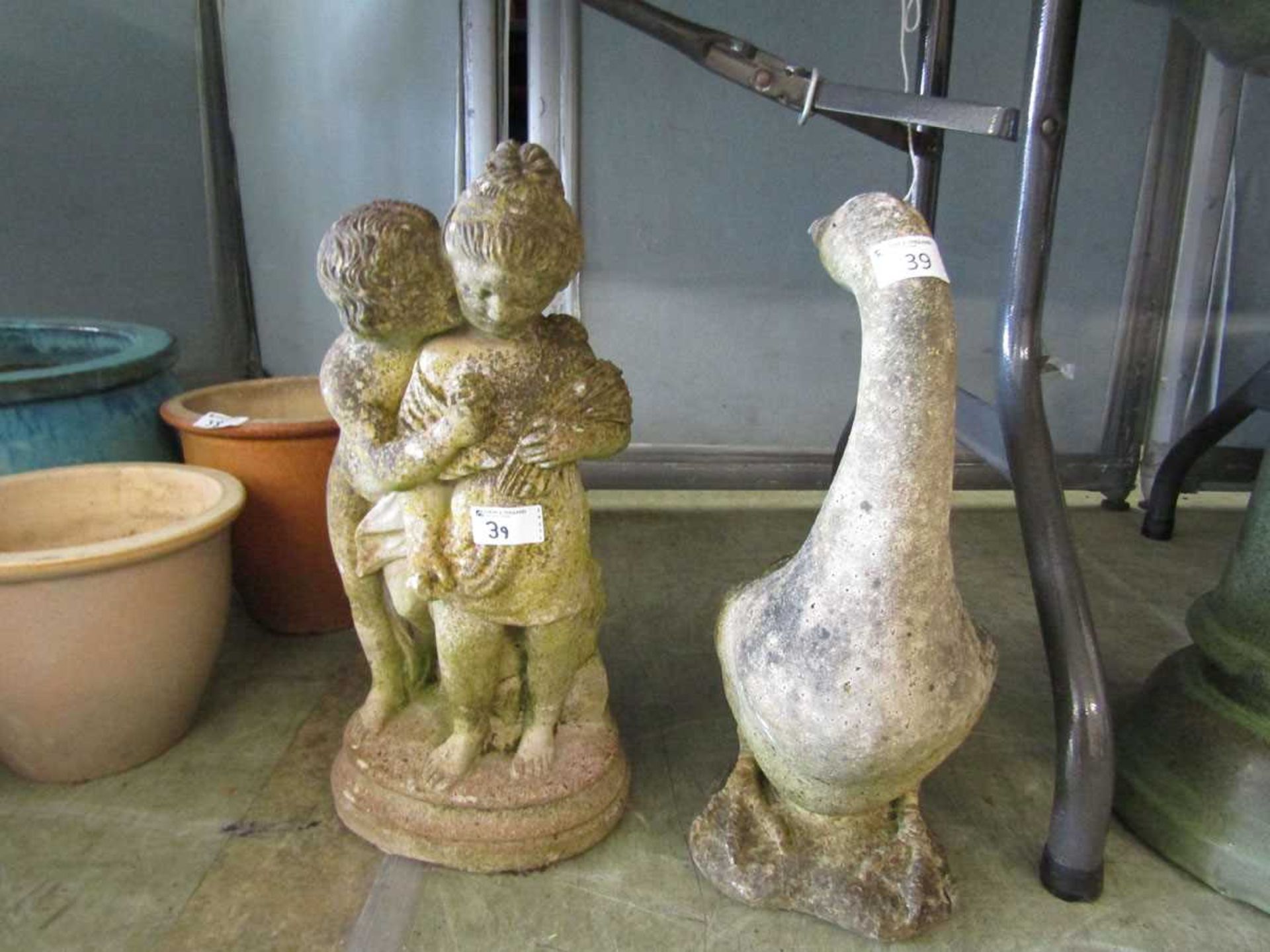 A weathered stoneware statue of a young girl together with a weathered stoneware statue of a goose
