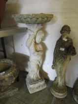 A weathered stoneware birdbath with cherub design