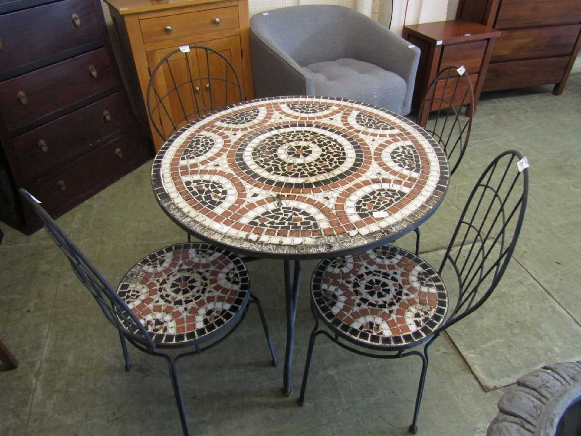 A specimen mosaic tiled top circular metal supported table with a set of four matching chairs