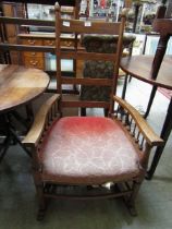 An early 20th century spindle armed rail back rocking chair