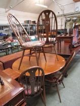 A light Ercol drop leaf table together with a set of four mid coloured elm wheel back chairs