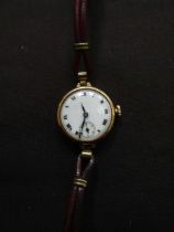 A ladies' yellow metal wristwatch marked '18' in case with leather strap
