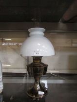 A brass based oil lamp with white glass shade