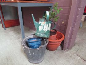 A selection of clay garden pots, painted watering can, and galvanised buckets