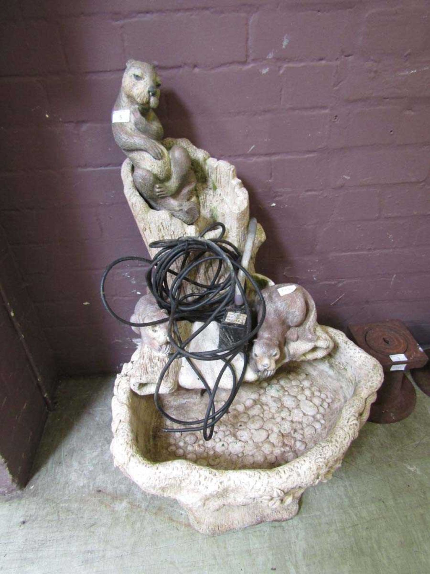 A stoneware garden water feature having otter design