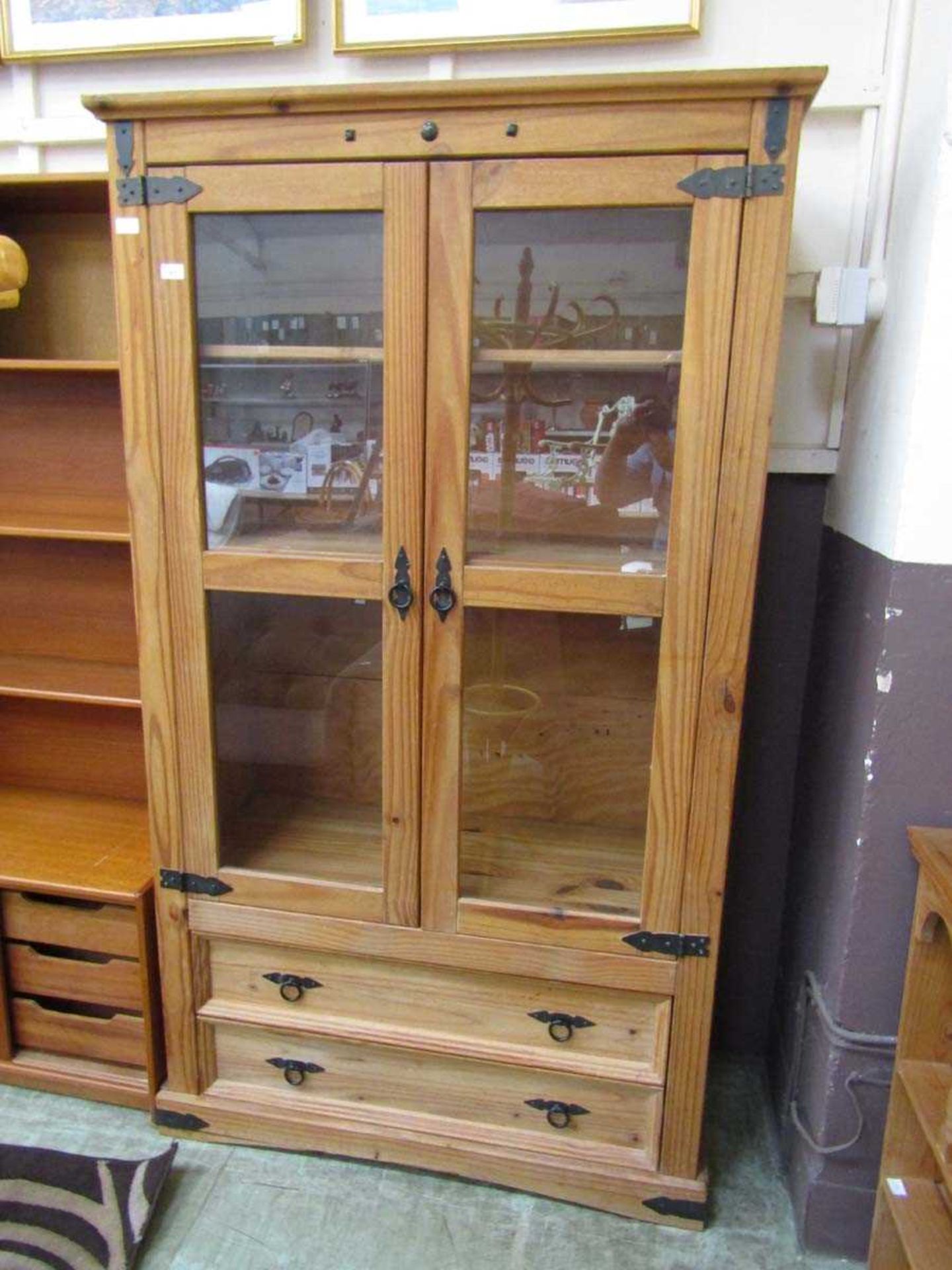A modern pine cabinet having two glazed doors above two drawers