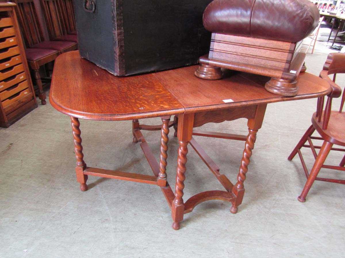 A mid-20th century oak gate leg table on barley twist supports