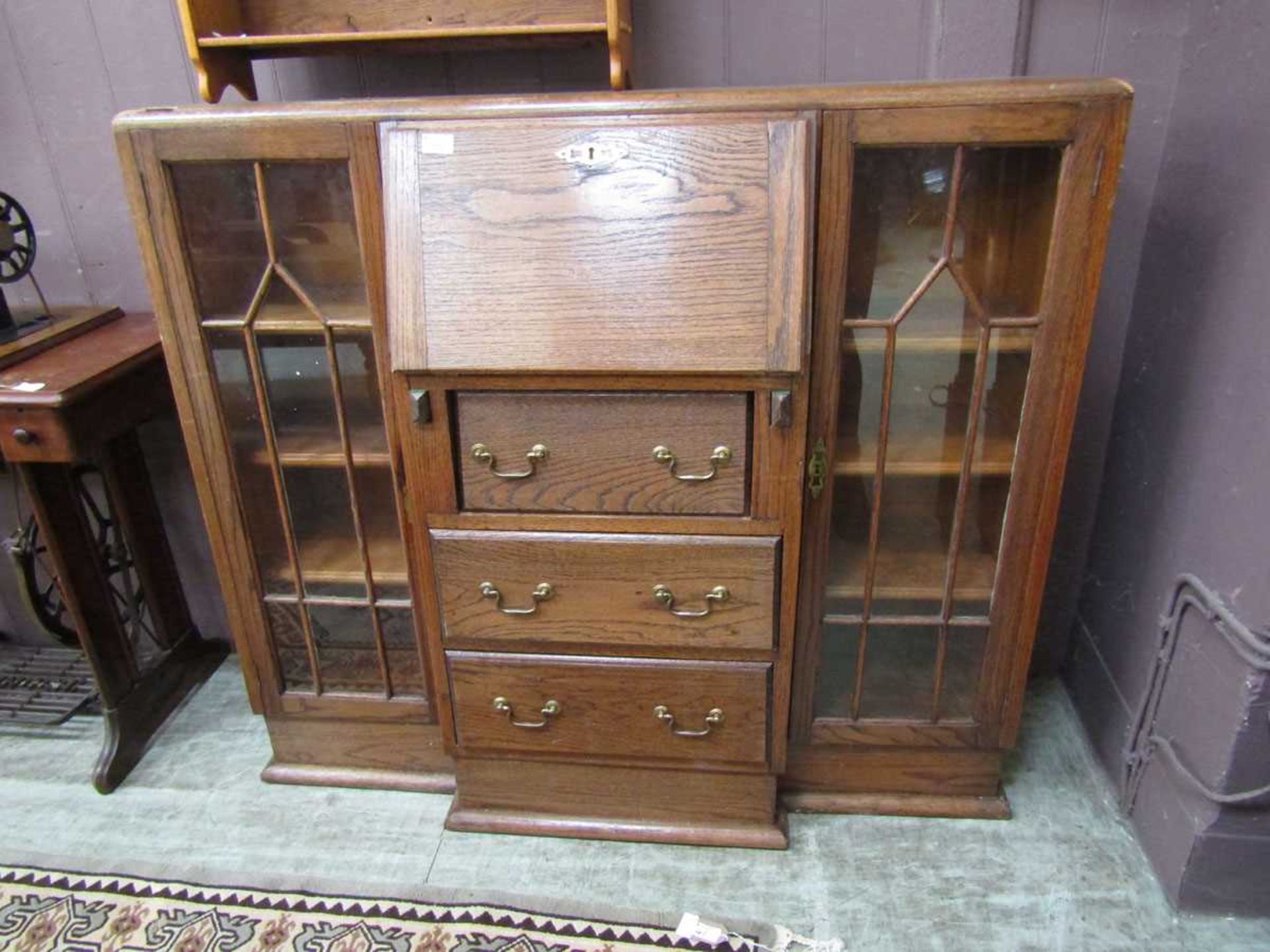 An early 20th century oak bureau bookcase, having a fall with three drawers being flanked by