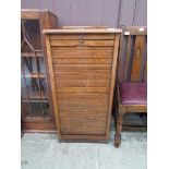 An early 20th century oak tambour fronted stationery cabinet having nine drawers